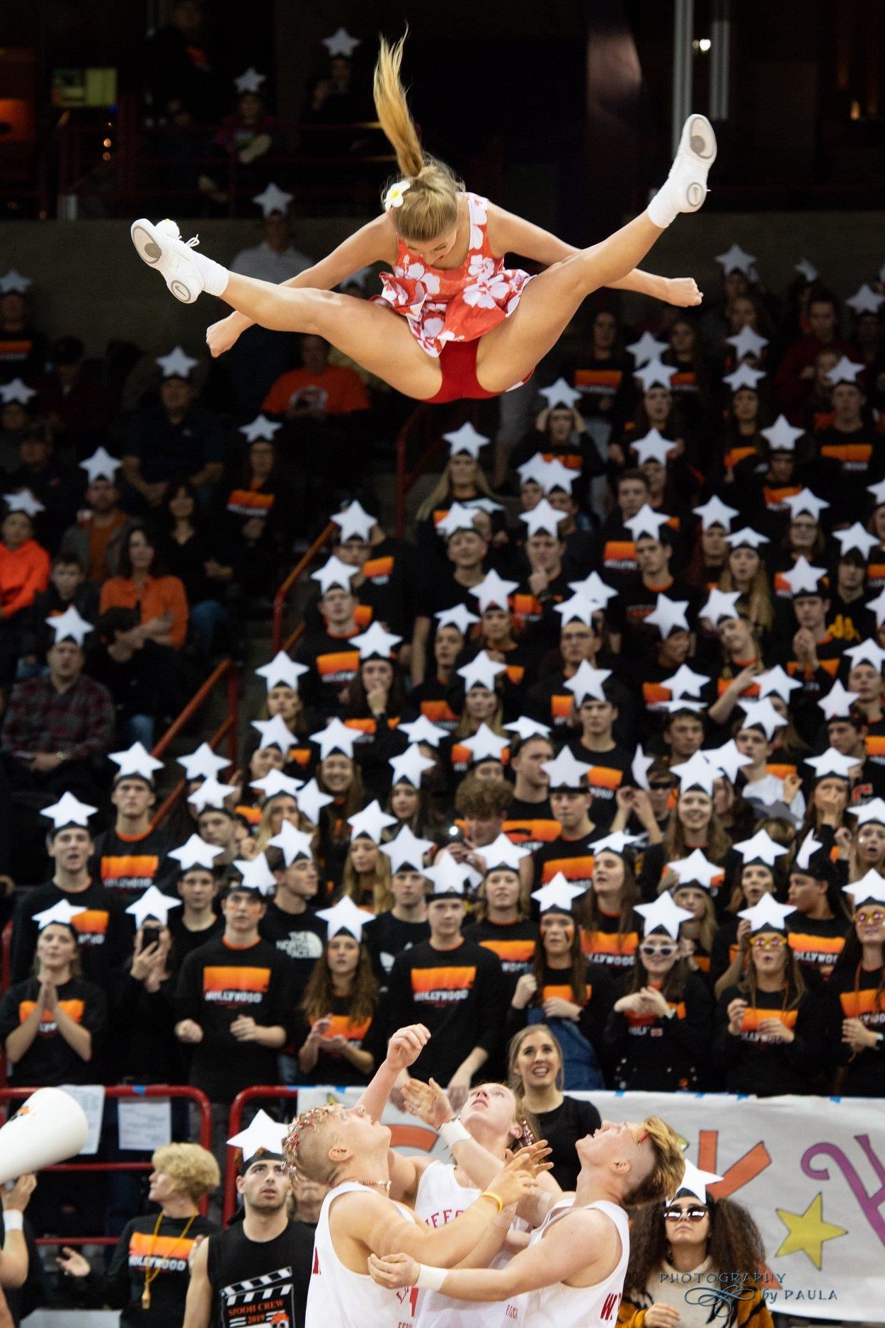 Photo of cheerleader performing basket toss toe touch