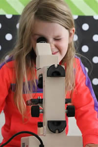 girl looking through microscope