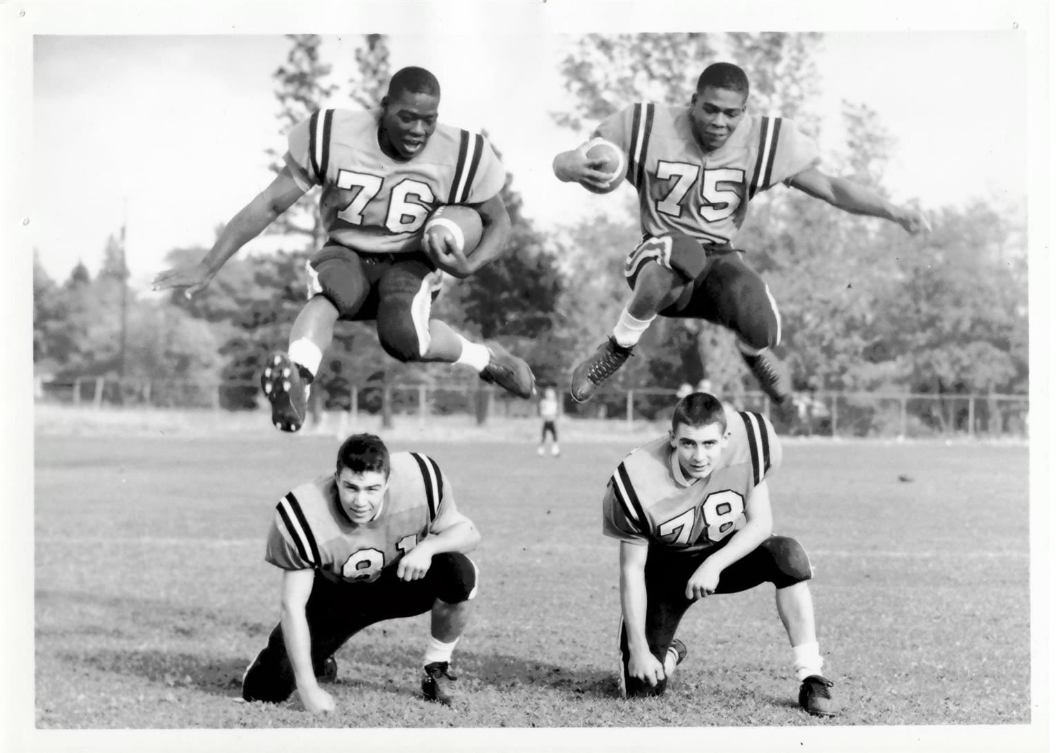 Two football players jumping over two other players for fun.